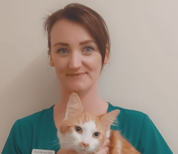 Image shows Kirsty Barnard smiling holding a ginger and white cat