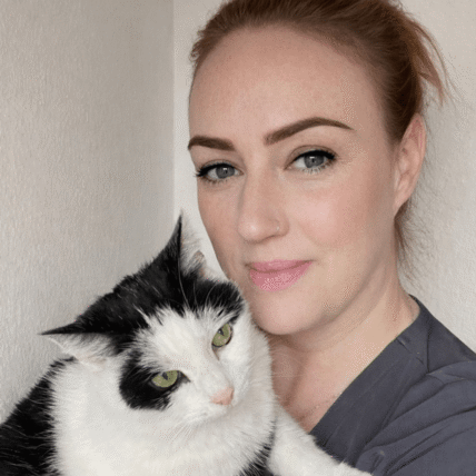 Sam Nelson, receptionist at Chorley Vets, holding a black and white cat while looking at the camera.